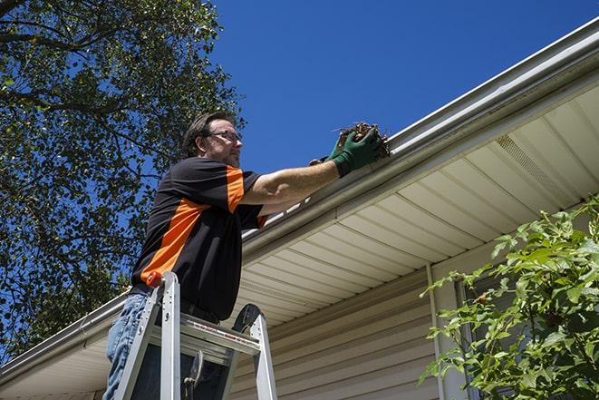 home improvement expert fixing gutters on a roof in Woodstock Valley, CT